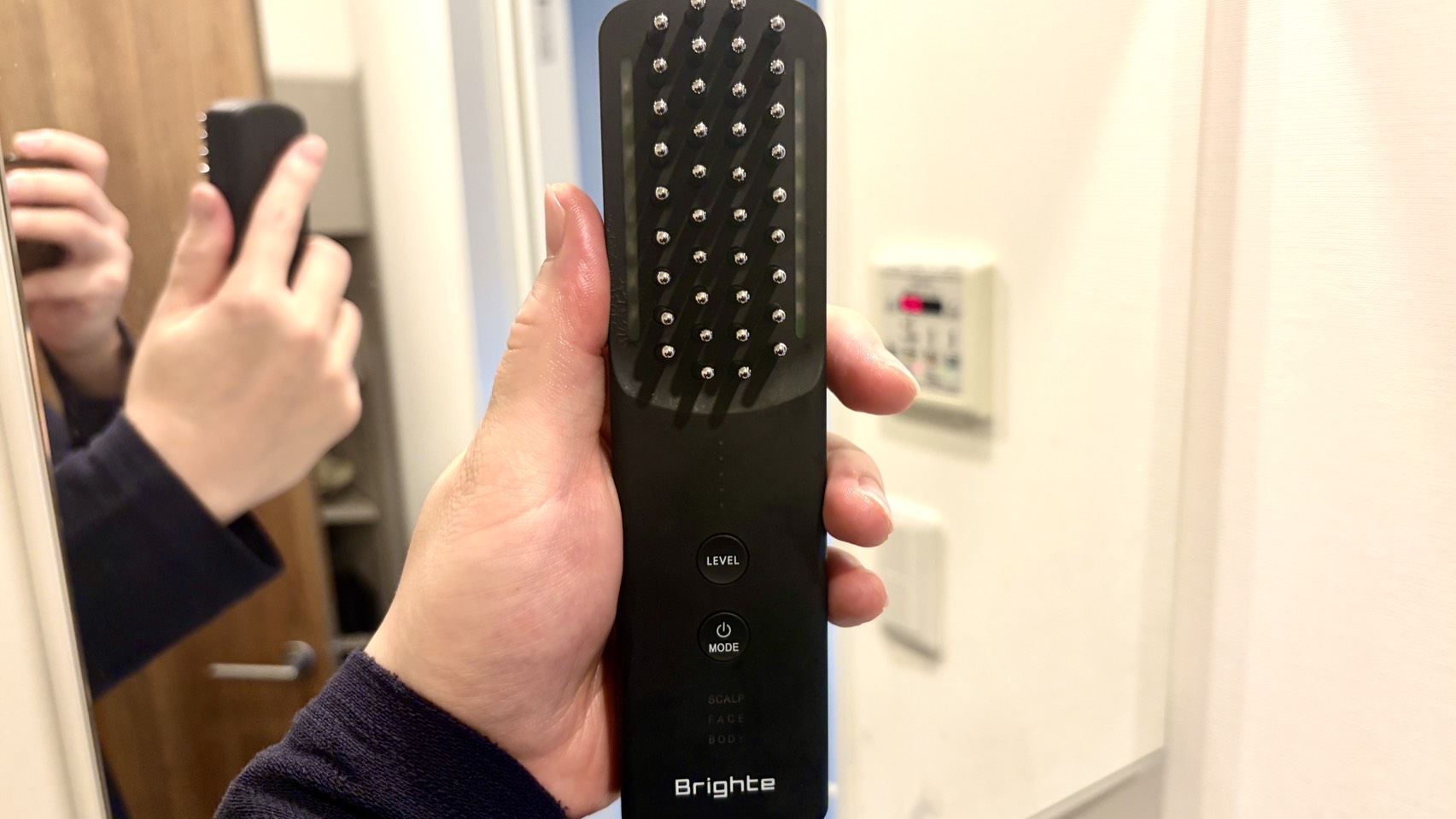 鏡の前でBrightエレキブラシを手に取っている様子